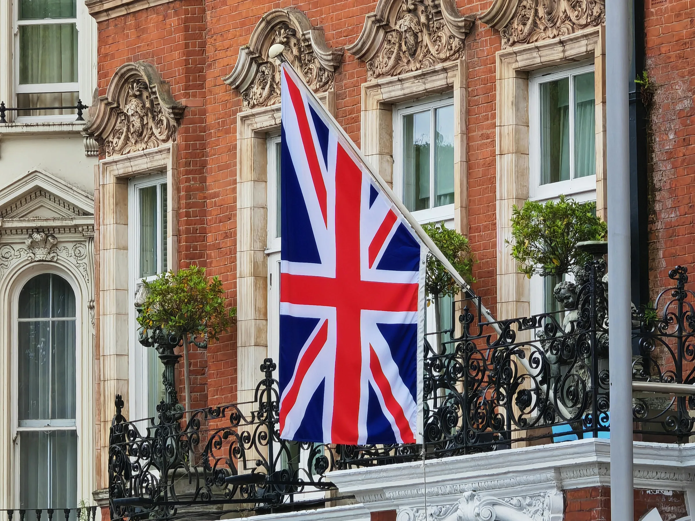 Drapeau britannique flottant sur un balcon en briques rouges.