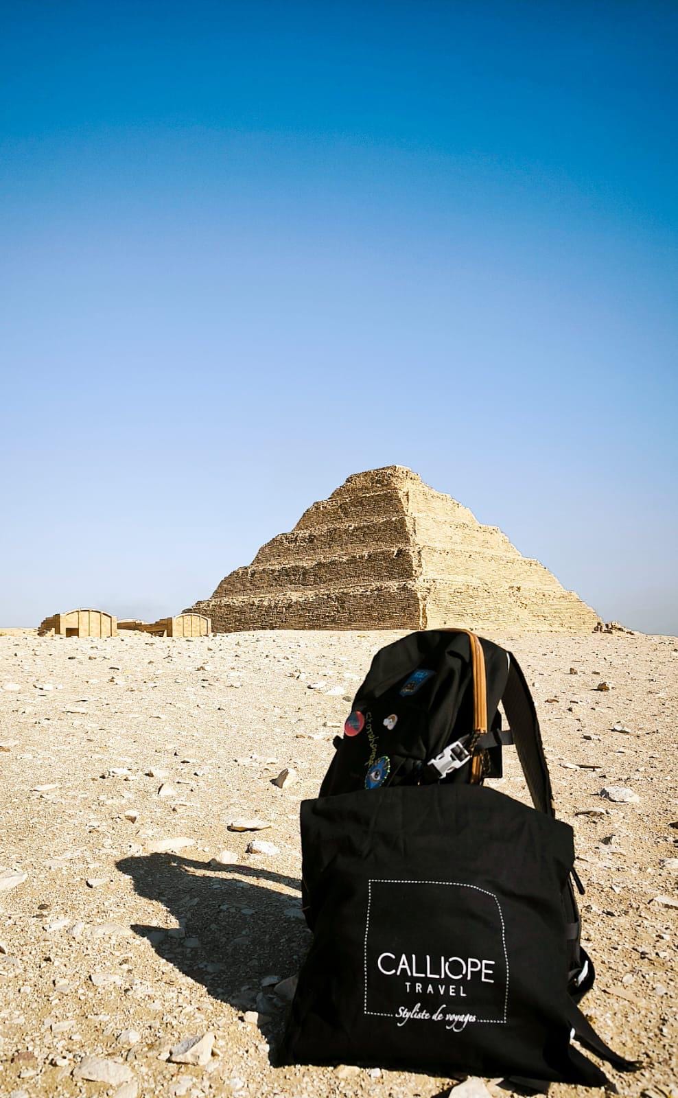 Un sac à dos noir avec le logo Calliope Travel devant une pyramide.