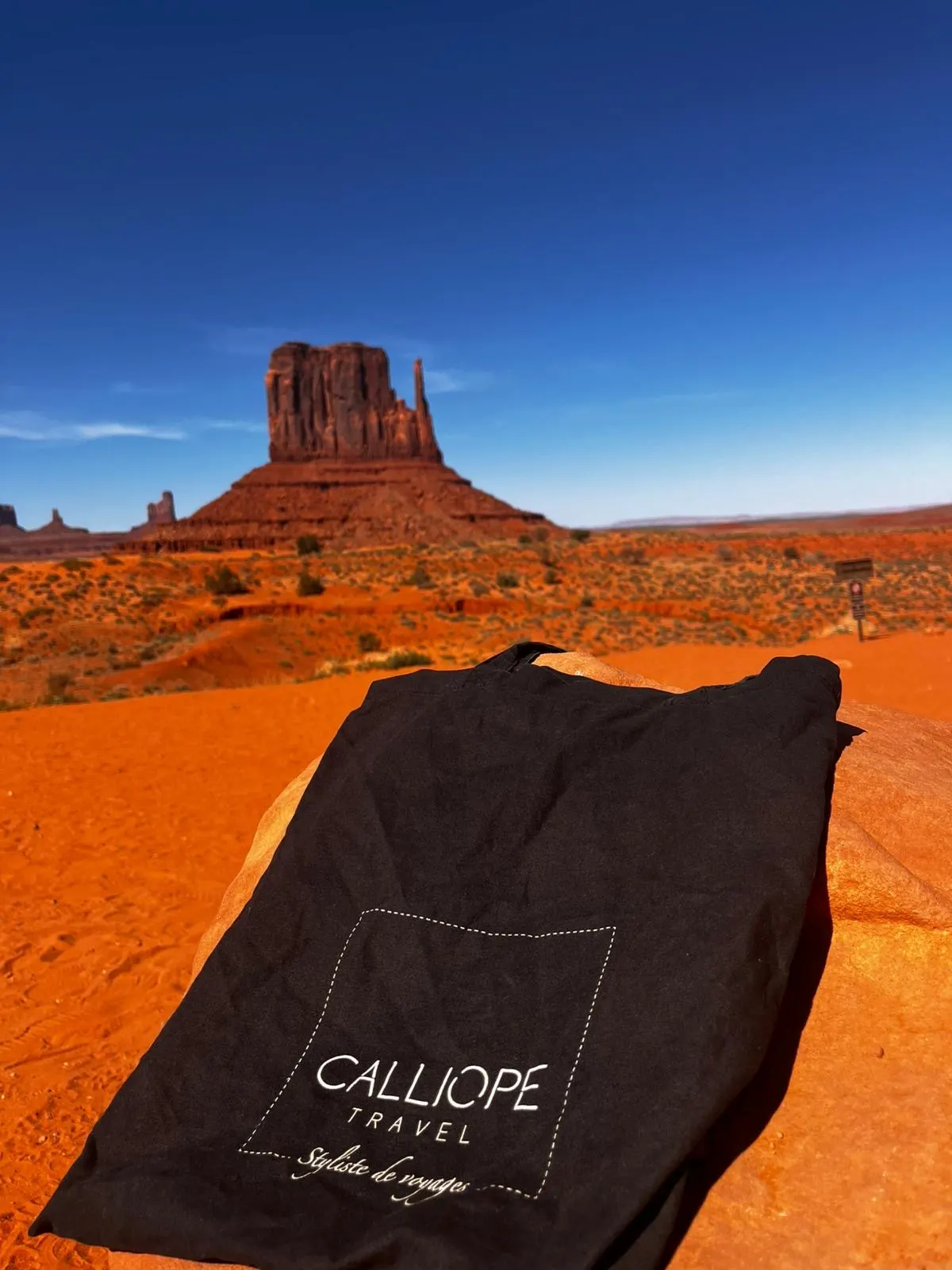 Sac noir de Calliope Travel avec un paysage désertique en arrière-plan.