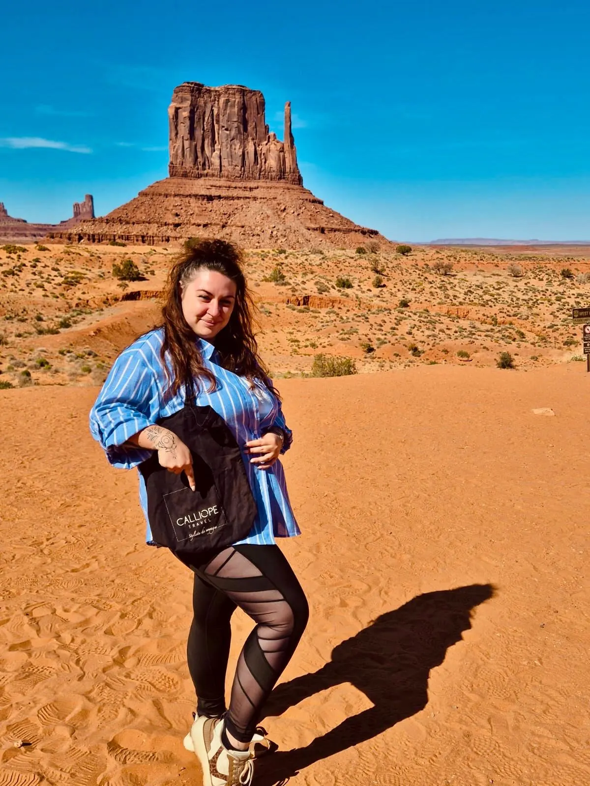 Femme posant dans le désert avec un paysage de monument rocheux en arrière-plan.