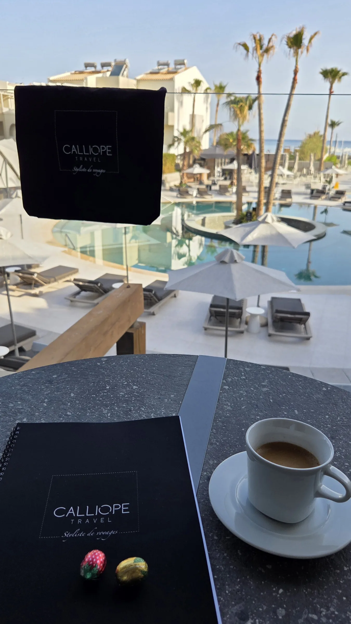 Vue d'une tasse de café et d'un carnet au bord d'une piscine.