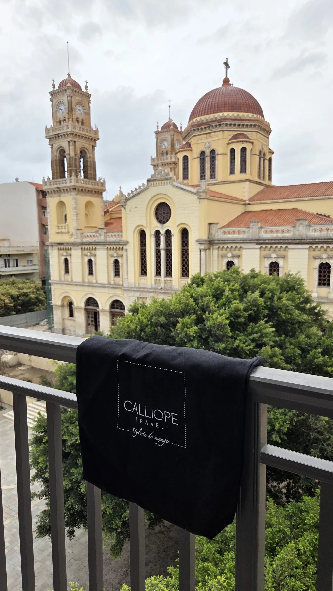 Vue d'un bâtiment historique avec un logo Calliope Travel sur un balcon.