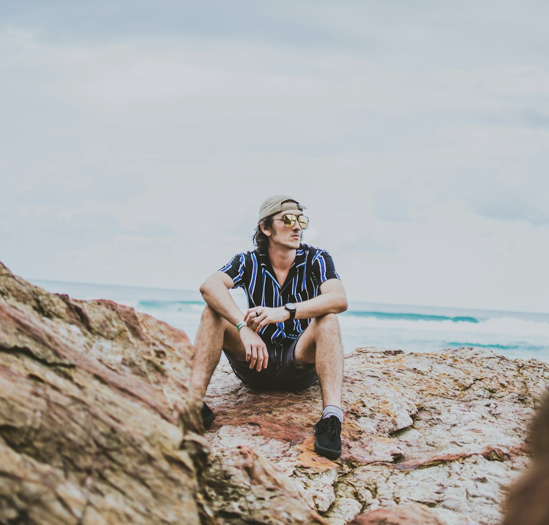 man sitting on brown rock