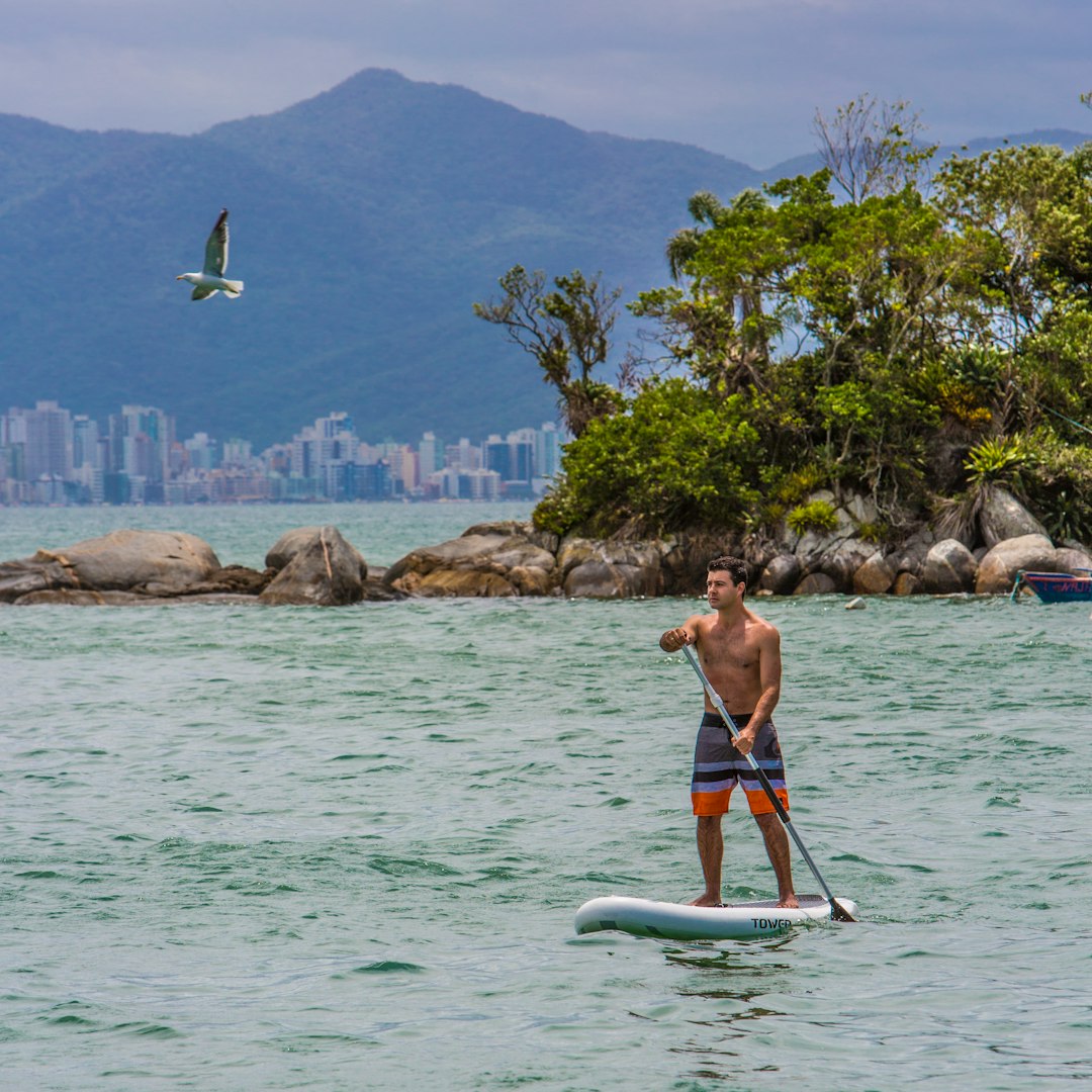 woman in red bikini sitting on white surfboard on body of water during daytime