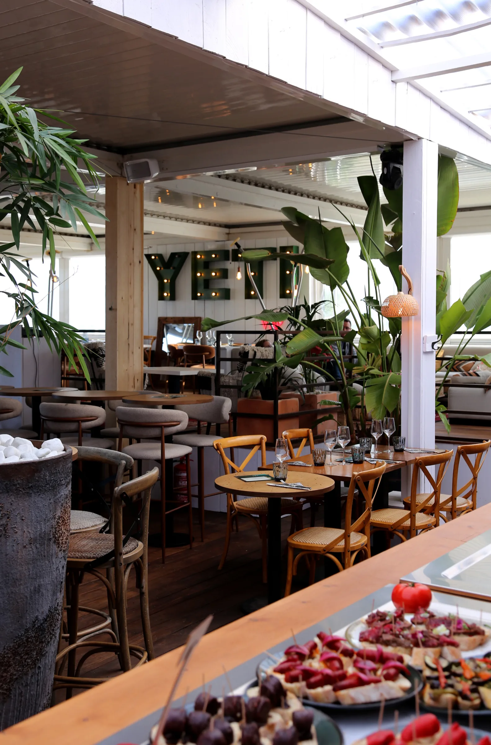 Interior view of YETI restaurant with tables and plants.