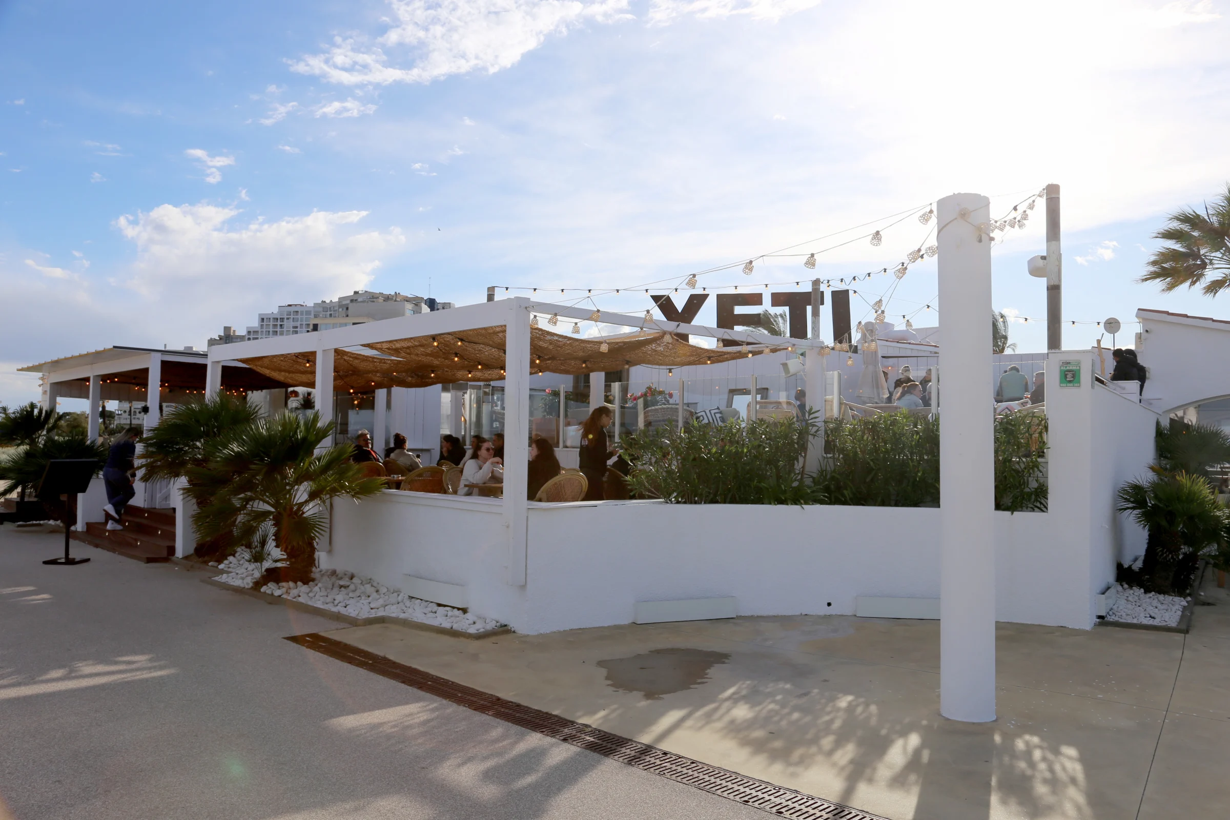 Outdoor dining area of YETI restaurant with palm trees and seating.