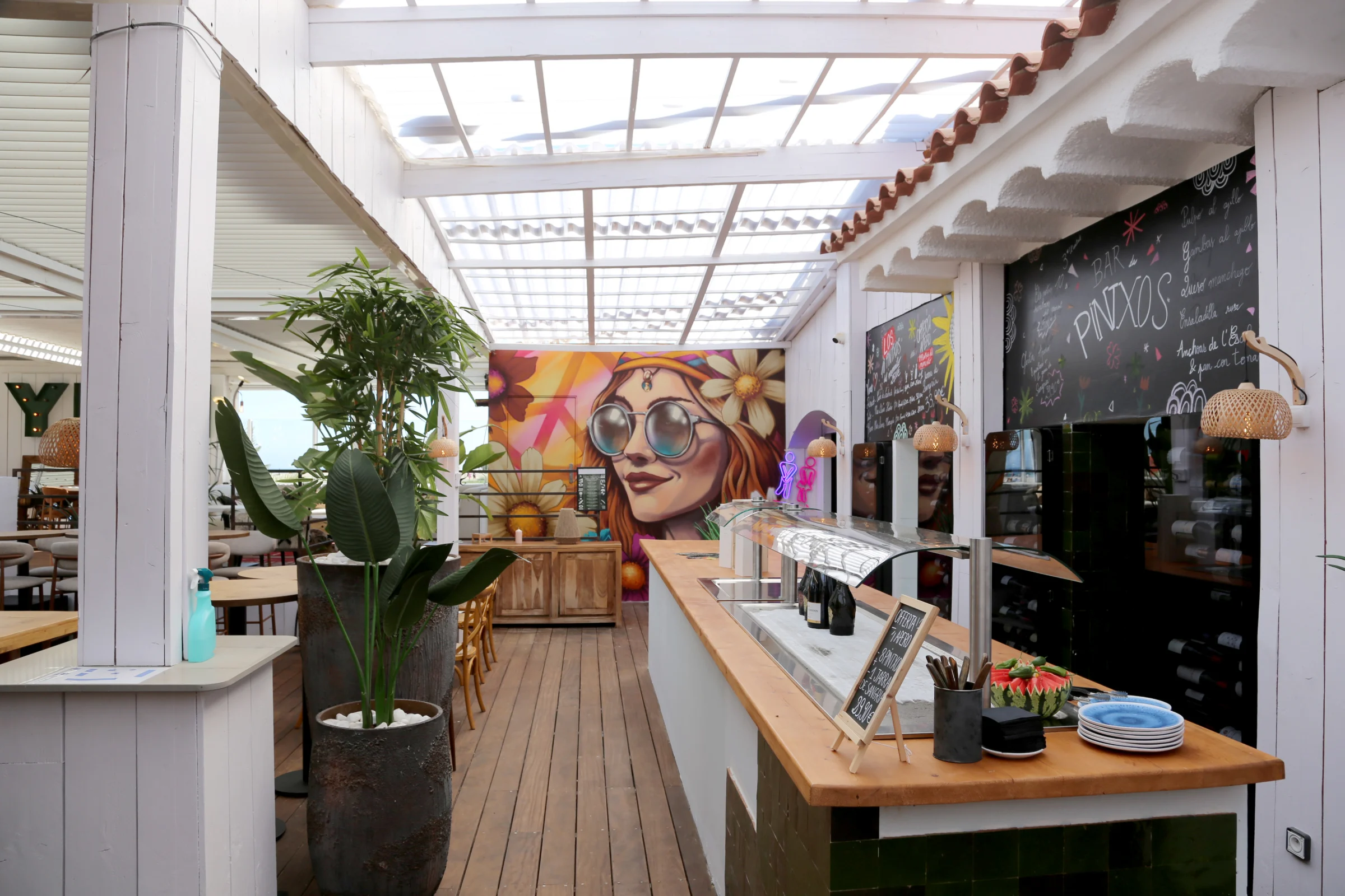 Interior of a restaurant with a vibrant mural and dining area.