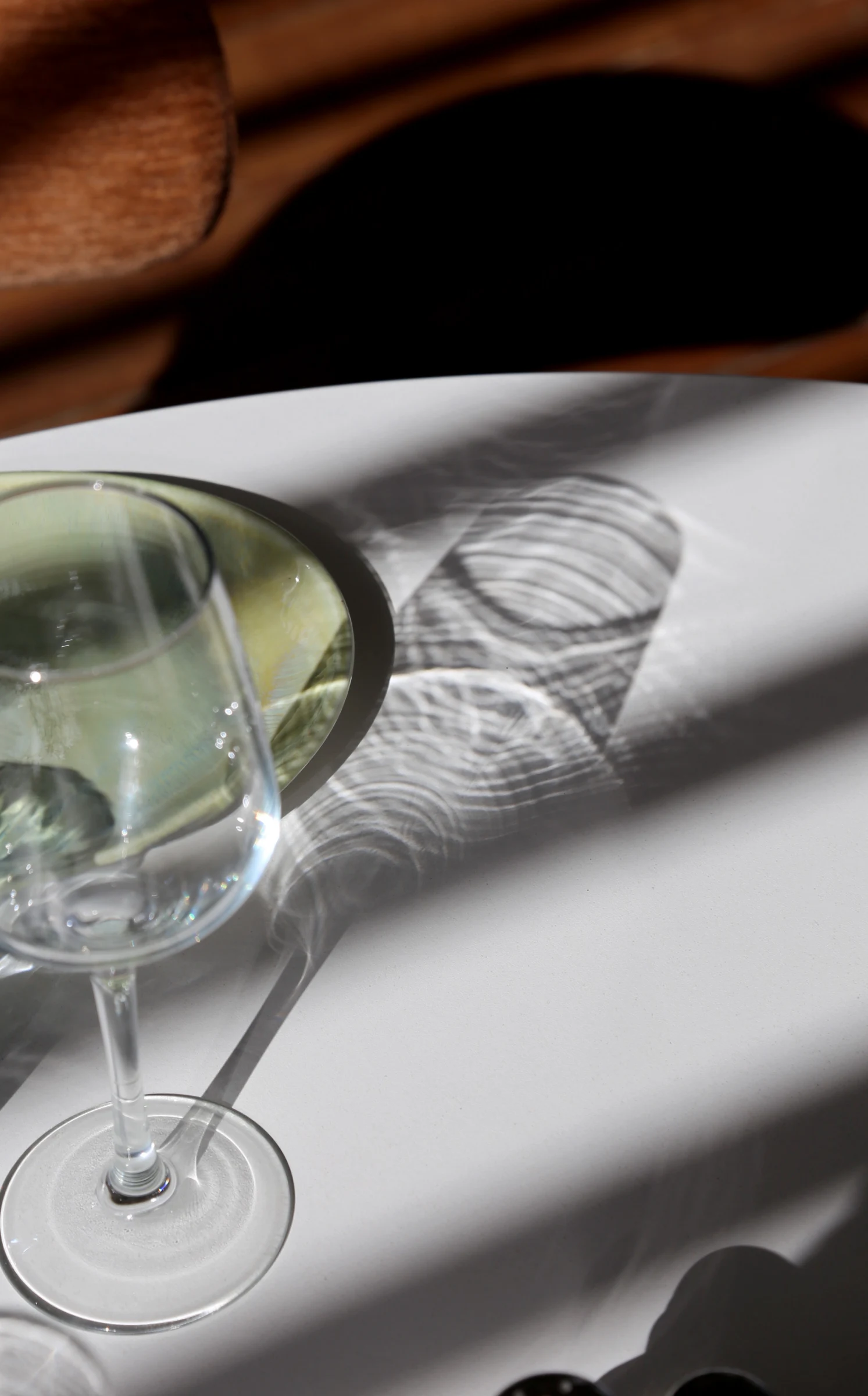 A glass and a plate casting shadows on a table.