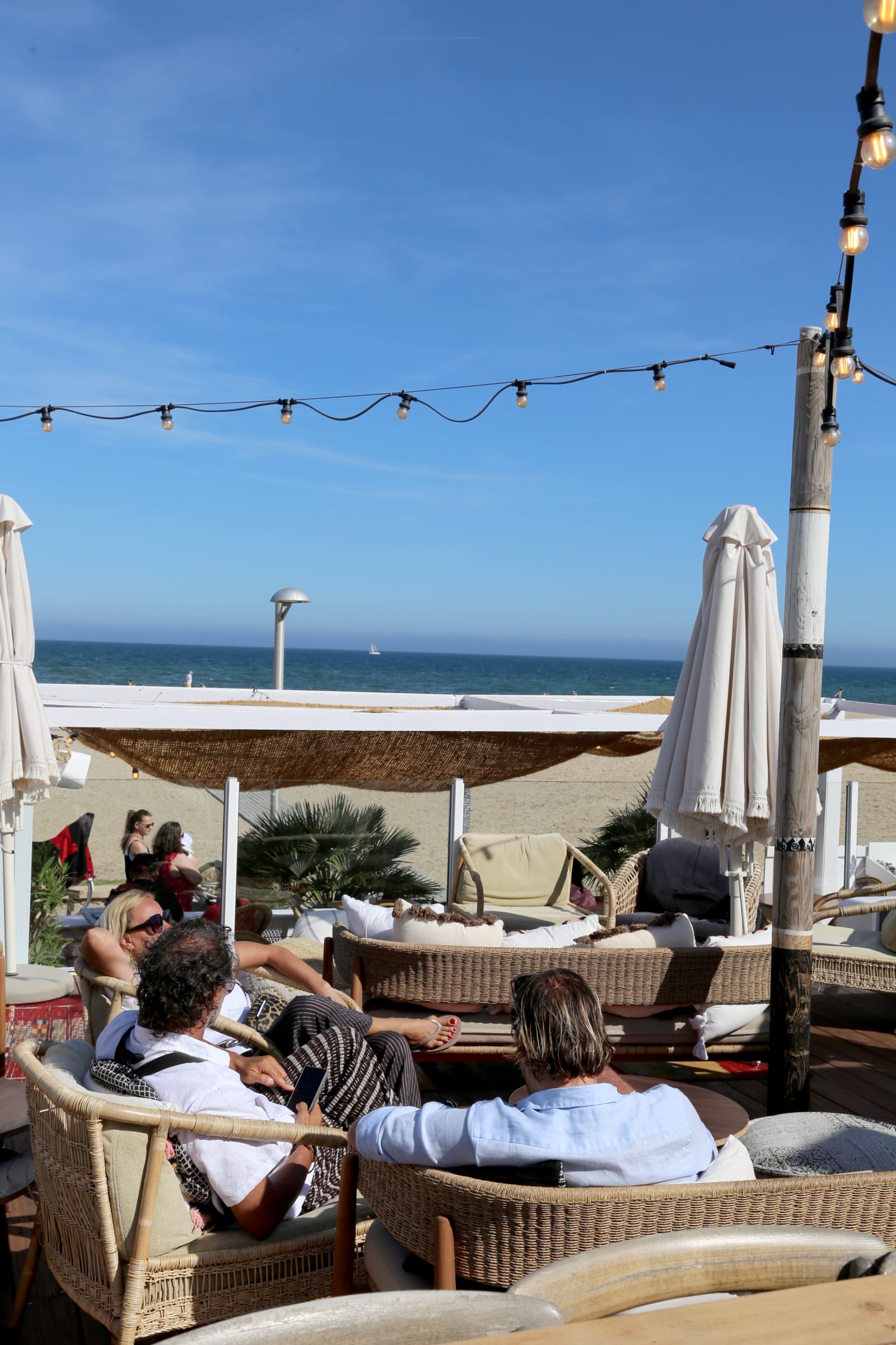People relaxing at a beachside restaurant with ocean view.