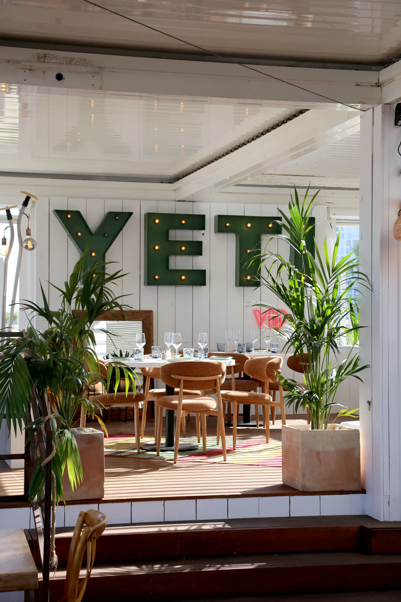 Interior view of YETI restaurant with green letters and plants.
