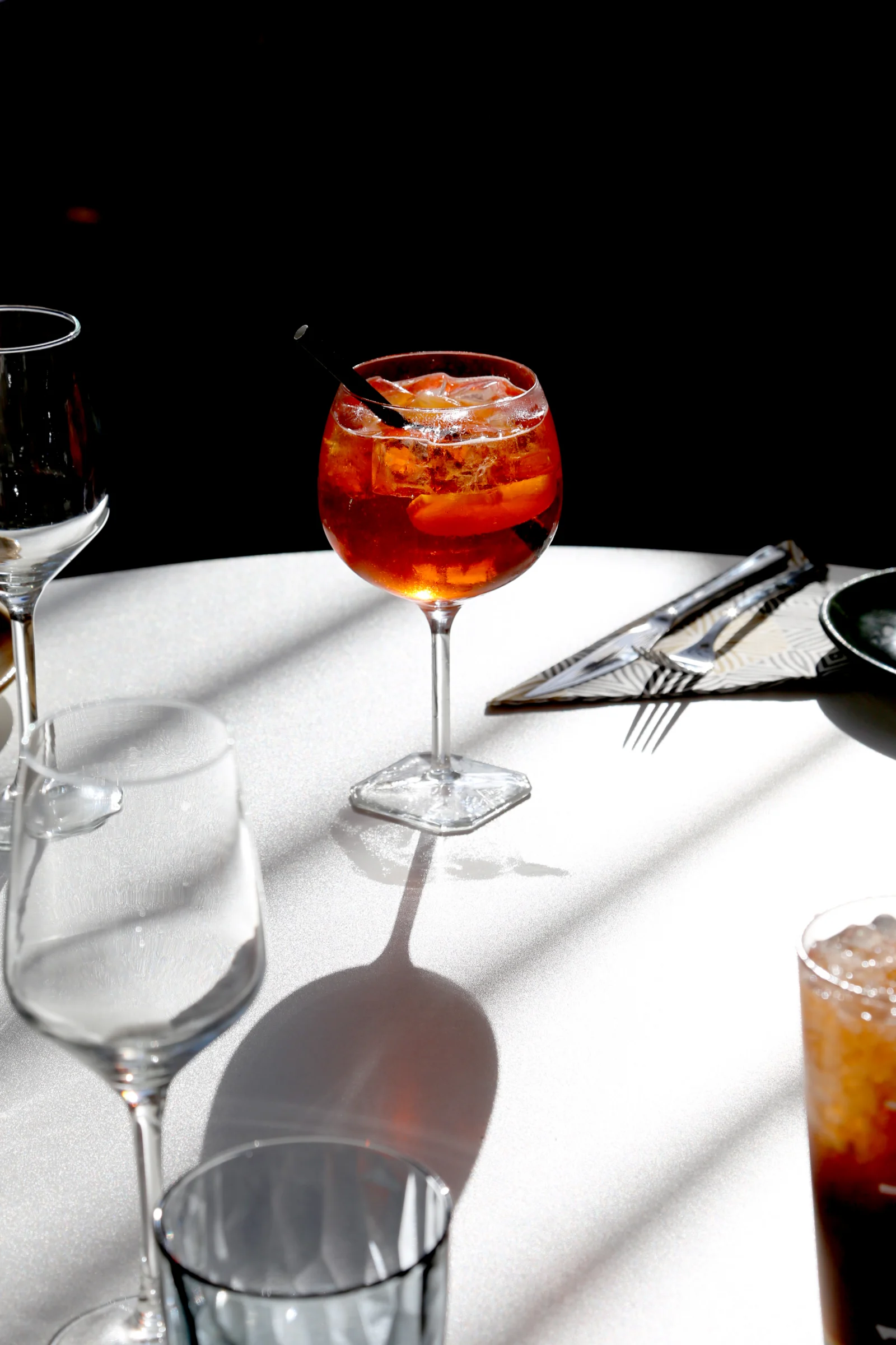 A cocktail glass with a straw and citrus slices on a table.