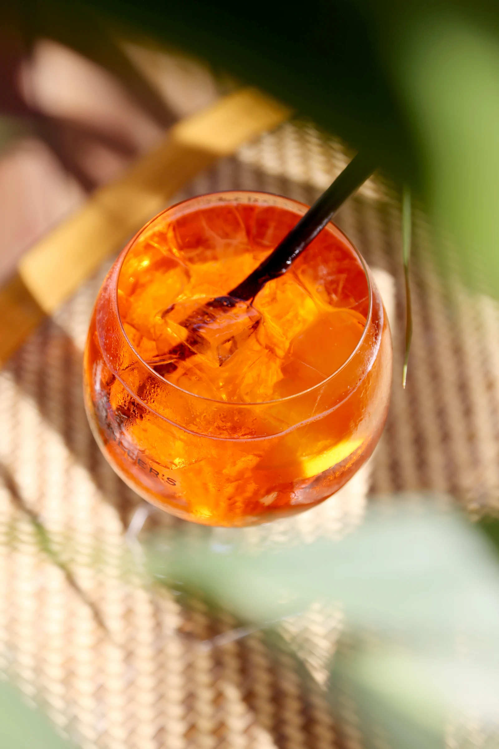A close-up of a vibrant orange cocktail in a glass with ice.