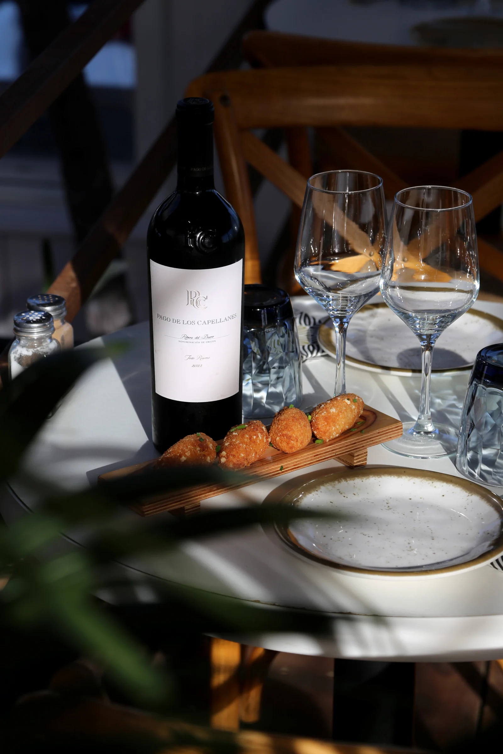 A bottle of wine with glasses and appetizers on a table