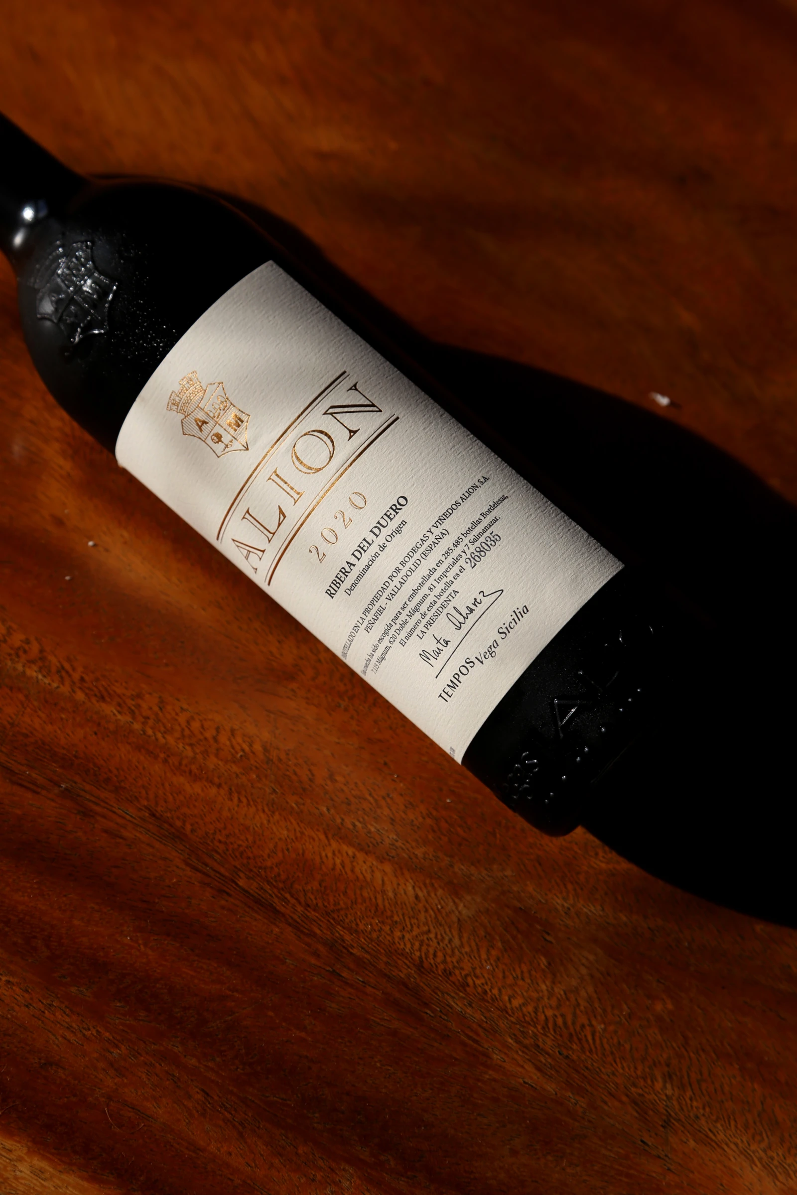 A bottle of Alion wine from 2020 on a wooden surface.