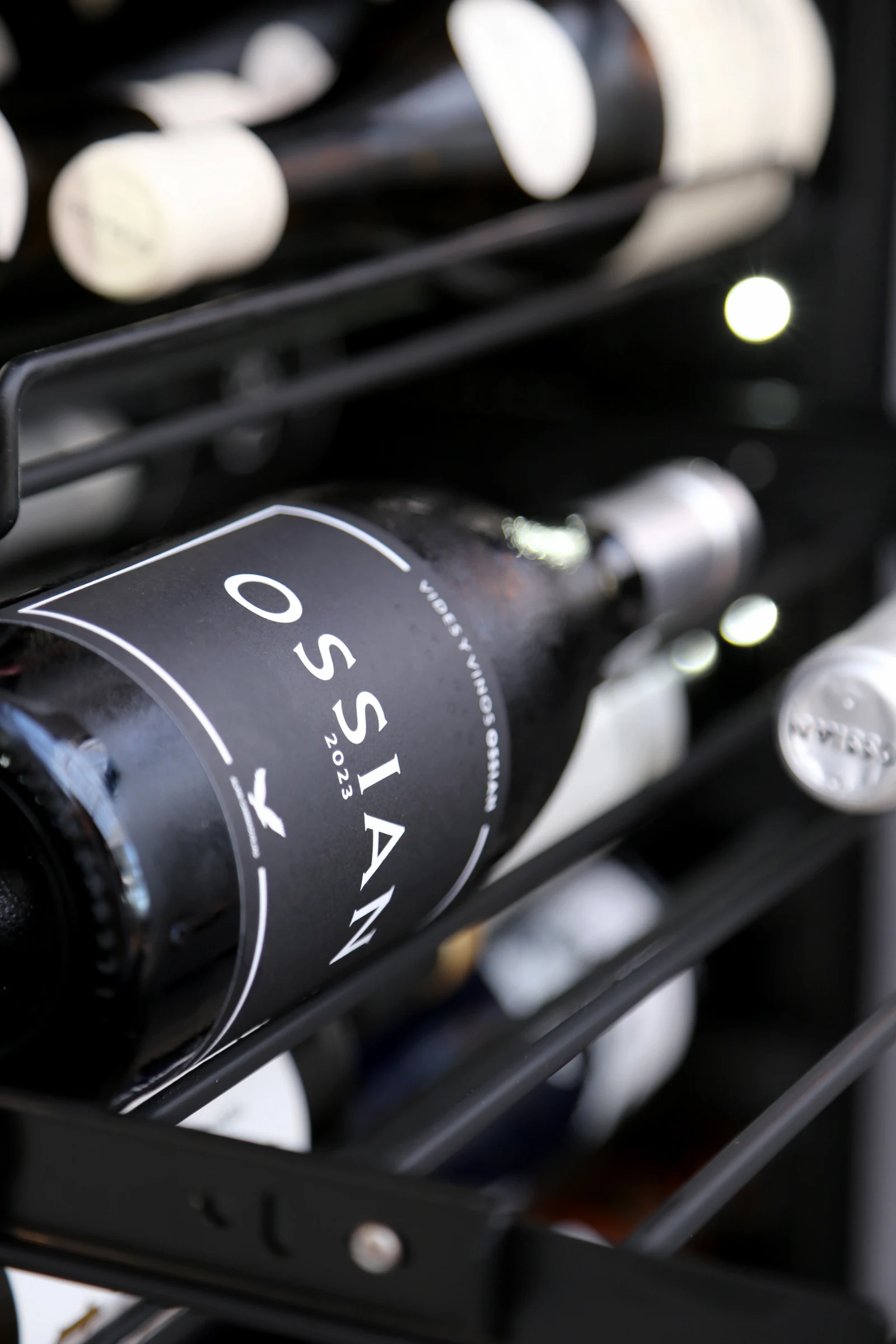 Close-up of a wine bottle labeled OSSIAN 2023 on a shelf.