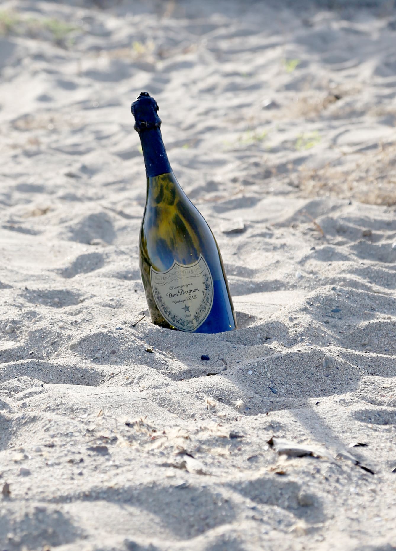 Champagne bottle partially buried in sand