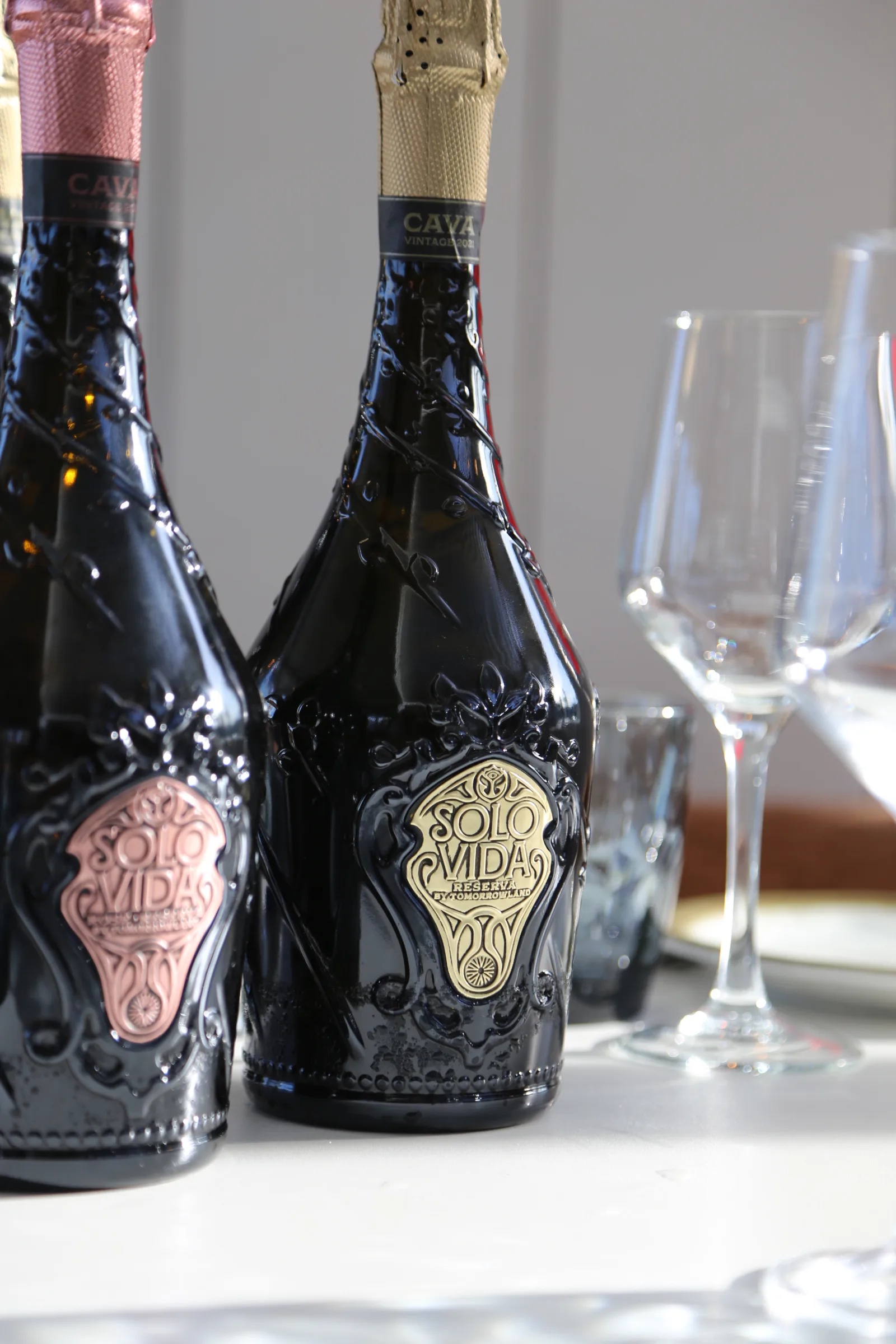 Two bottles of Solo Vida cava with glasses in the background