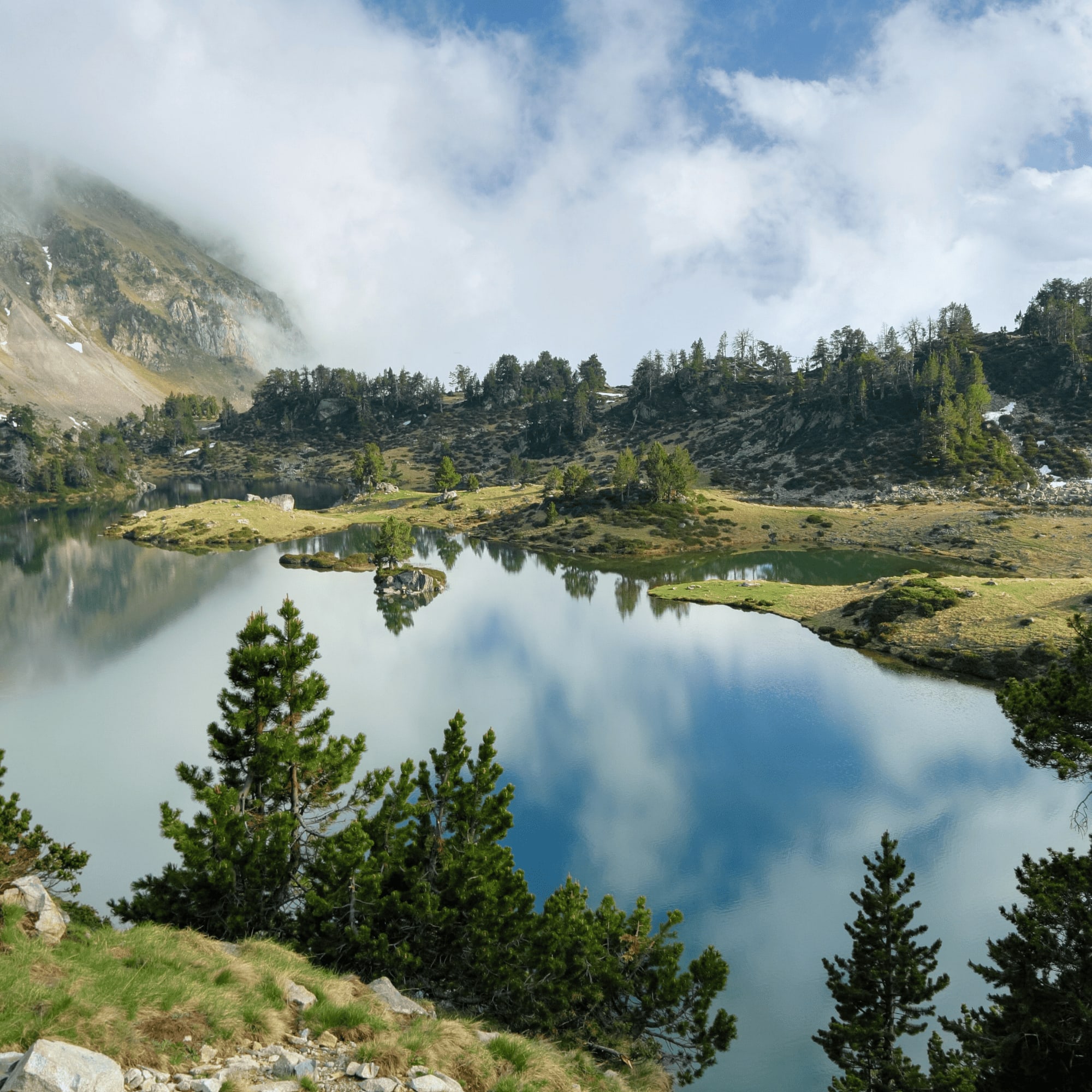 Lac paisible entouré de montagnes et de forêts verdoyantes.