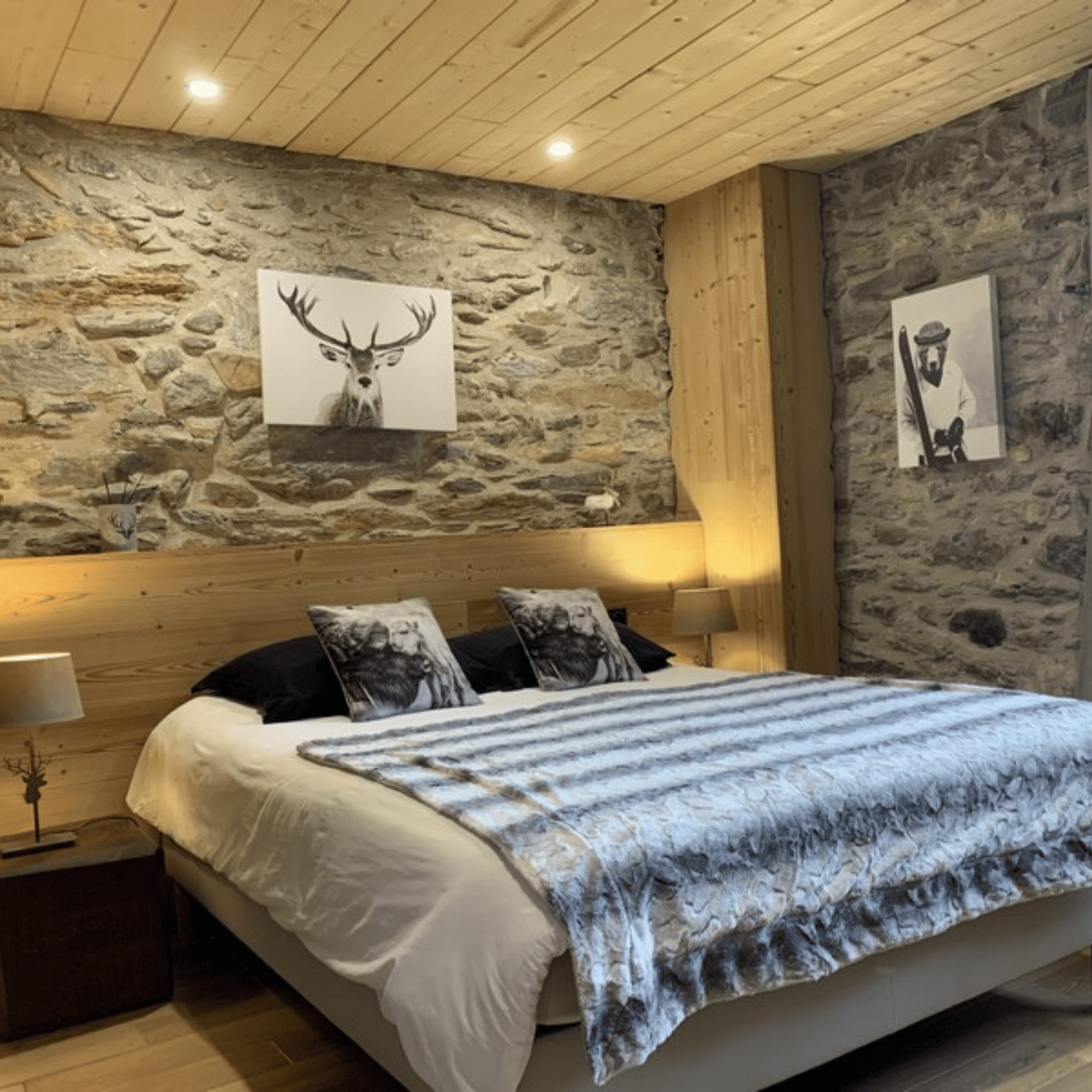 Chambre de chalet avec lit, décor en pierre et œuvres d'art
