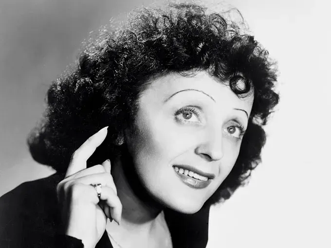 Femme avec des cheveux bouclés, souriant et pointant un doigt vers le haut.